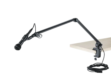 K&M microphone desk arm in black mounted on studio desk with microphone installed
